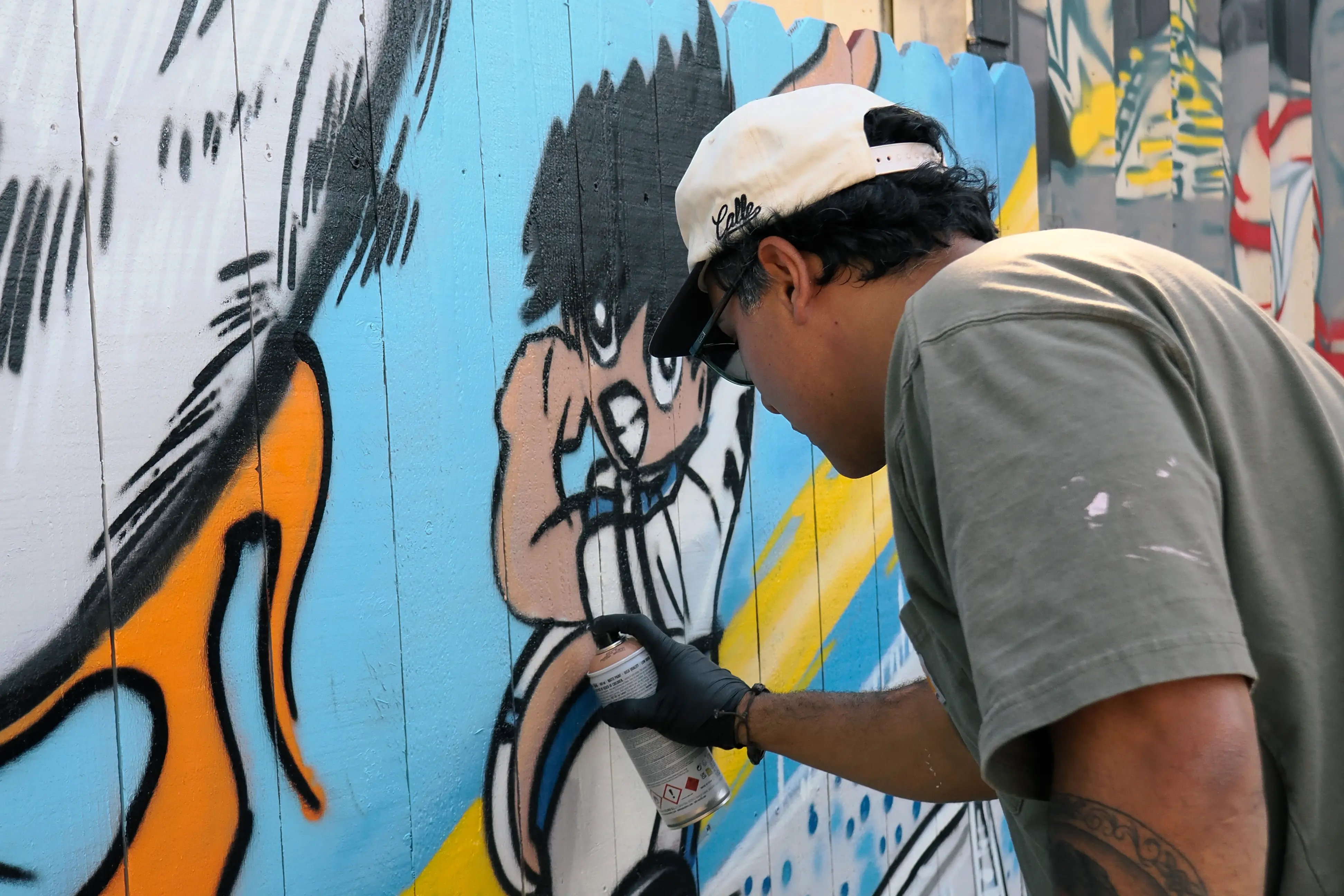 Artist spray-painting the character mural on the court wall
