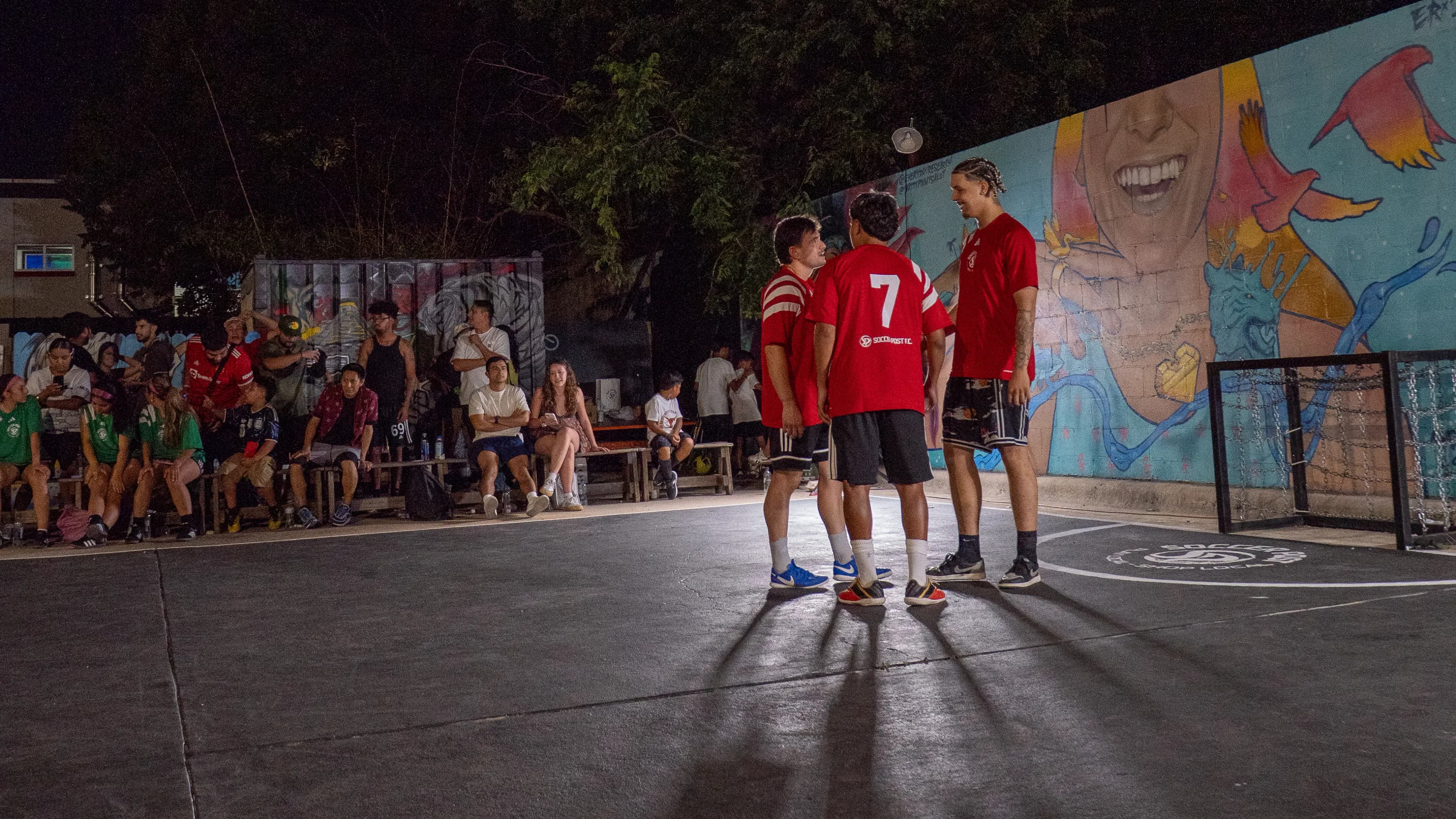 Players in numbered red kits under the court lights